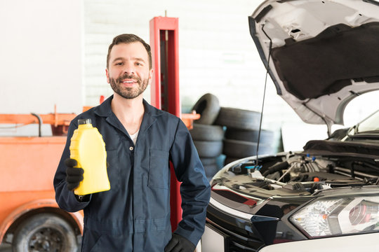 Smiling Mechanic With Motor Oil Can Standing In Garage