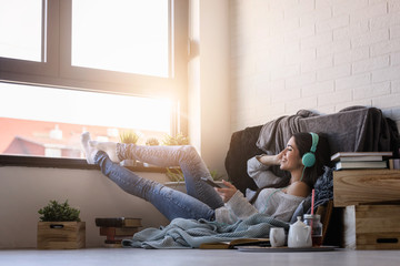 Beautiful young woman at home enjoys listening music through headphones