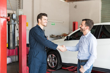 Customer Shaking Hands With Car Mechanic At Repair Shop