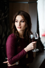 Elegant brunette lady with glass of red wine in restaurant.