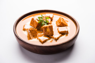 Paneer Butter Masala also known as Panir  makhani or makhanwala. served in a ceramic or terracotta bowl with fresh cream and coriander. Isolated over colourful moody background. selective focus