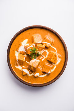 Paneer Butter Masala also known as Panir  makhani or makhanwala. served in a ceramic or terracotta bowl with fresh cream and coriander. Isolated over colourful moody background. selective focus