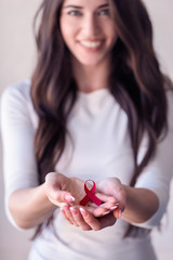 Woman holding red ribbon on her palms. AIDS awareness symbol