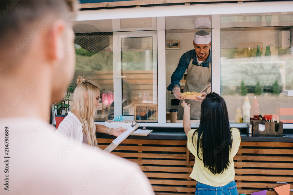 Wall mural selective focus of young people buying fast food at food truck