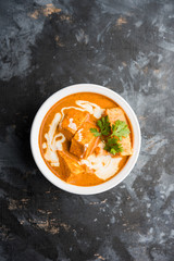 Paneer Butter Masala also known as Panir  makhani or makhanwala. served in a ceramic or terracotta bowl with fresh cream and coriander. Isolated over colourful moody background. selective focus