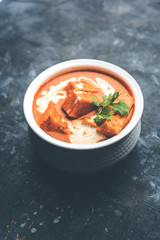 Paneer Butter Masala also known as Panir  makhani or makhanwala. served in a ceramic or terracotta bowl with fresh cream and coriander. Isolated over colourful moody background. selective focus