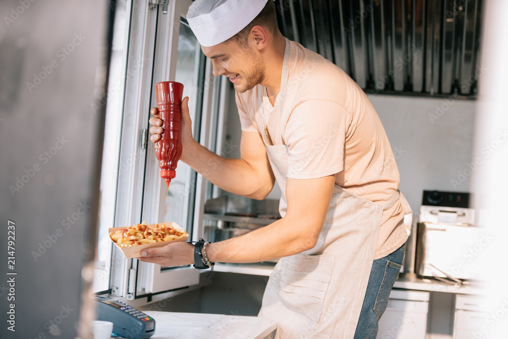 Sticker side view of chef adding ketchup to hot dog in food truck