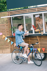 Chef giving hot dog and ketchup to customer from food truck