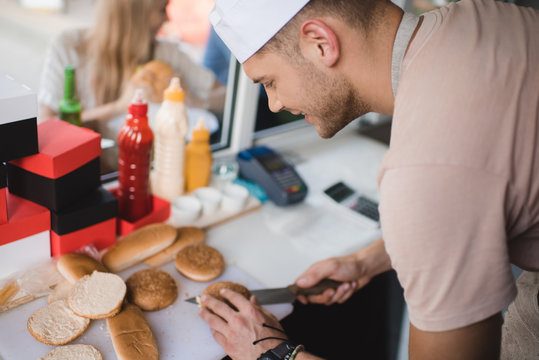 Side View Of Chef Cutting Bun With Knife In Food Truck