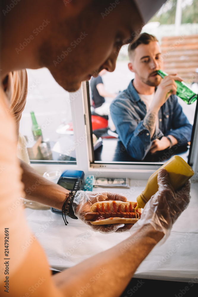 Wall mural chef preparing hod dog in food truck, customer drinking beer