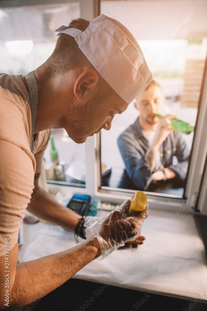 Poster chef preparing hod dog in food truck