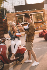 boyfriend feeding girlfriend with french fries near food truck