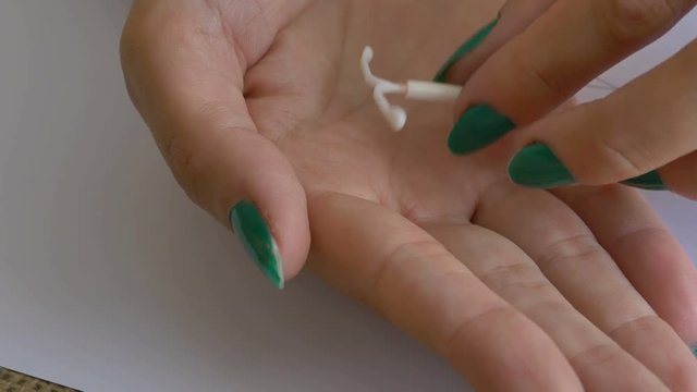 Woman showing a birth control device (IUD) in her palm.