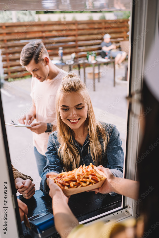 Wall mural cropped image of chef giving french fries to customer in food truck