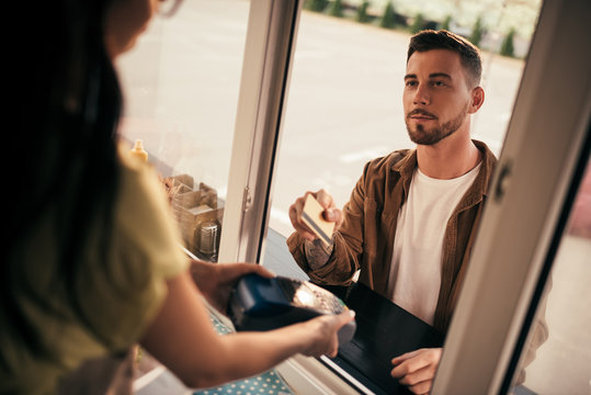 cropped image of handsome customer paying with credit card for food at food truck