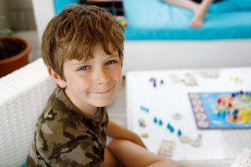 Little adorable school kid boy playing board game with family. Schoolkid and child having fun with...