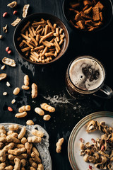 top view of table set with snacks and glass of beer on dark wooden surface