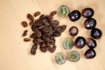 Raisins and red grapes on a wooden background