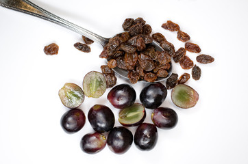 Spoonful of raisins with red grapes on a white background