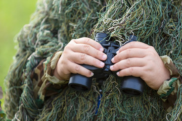 Bird watcher in ghillie suit hold binoculars for bird education