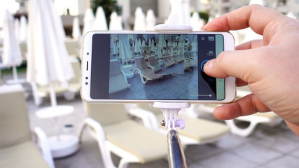 A blogger on vacation makes a photo using a smartphone. A man takes pictures of sun beds and...