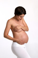 Schwangere Frau mit nacktem Oberkörper lächelt und hält sich den Bauch 