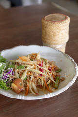 Thai papaya salad or Som Tum and sticky rice is popular thai food on wood table