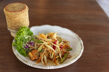 Thai papaya salad or Som Tum and sticky rice is popular thai food on wood table