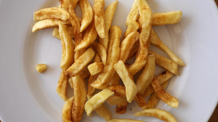 Fried potatoes, French chips are spinning on a plate.