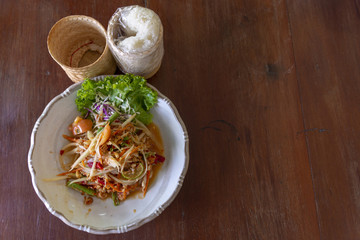 Thai papaya salad or Som Tum and sticky rice is popular thai food on wood table