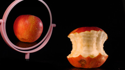 Concept of beauty and transfiguration. The apple stub looks into the mirror and dreams of becoming an apple.