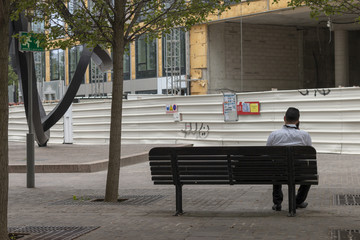 Man in shirt sitting alone on a bench on the phone