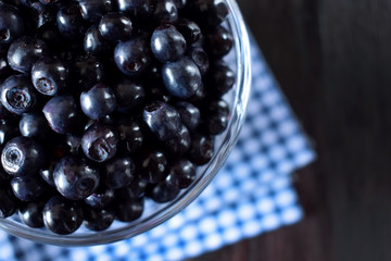 Close-up of bilberries in a glass cup against the dark background