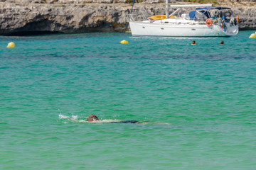 man in a scuba mask swims in blue sea water