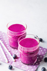 Blueberry smoothies in wooden box on white stone background. 