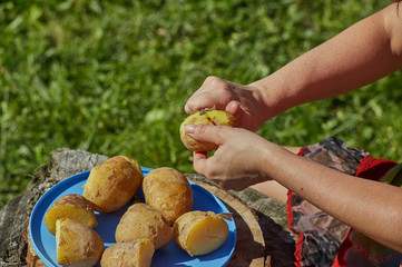 Woman peeling boiled potatoe.