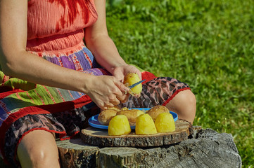 Woman peeling boiled potatoe.