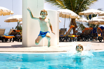 Two happy little kids boys jumping in the pool and having fun on family vacations in a hotel...