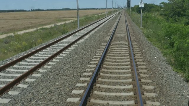Running railroad with metal rails and gravel view.