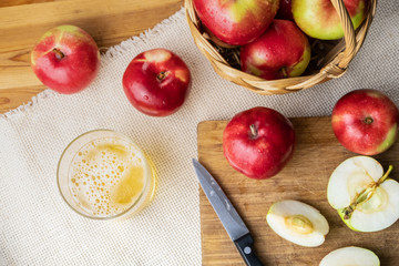 Top view of ripe juicy apples and glass of cidre drink on rustic wooden table. Glass of home made cider and locally grown organic apples, shot from above