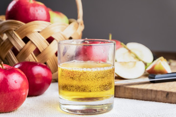 Close-up image of cidre drink and ripe juicy apples on rustic wooden table. Glass of home made cider and locally grown organic apples