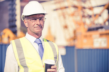 Engineer builder on construction site at sunny day with coffee i