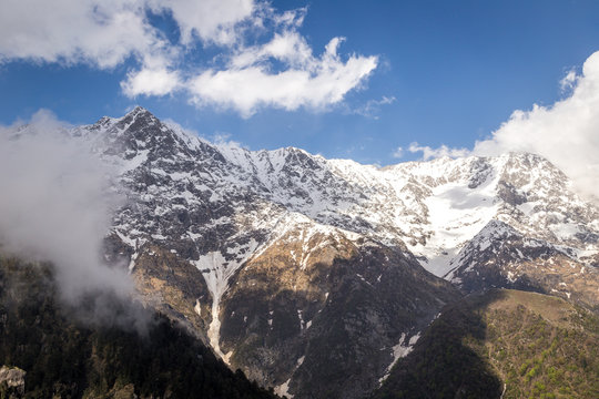 Scenic Triund mountains covered by white snow with cloudy blue skies, Mcleod ganj, Snow Line, Himachal Pradesh, India.
