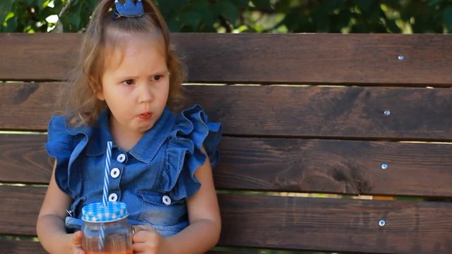 Child girl drinks smoothies in the park on a sunny day. Close up