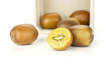 Lot of whole one half of fresh golden brown kiwi fruit sungold variety and a light wooden crate...
