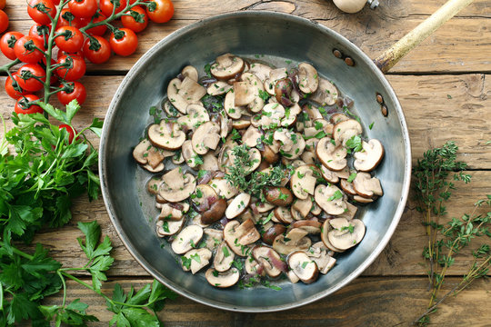 funghi trifolati in tegame di metallo sfondo rustico