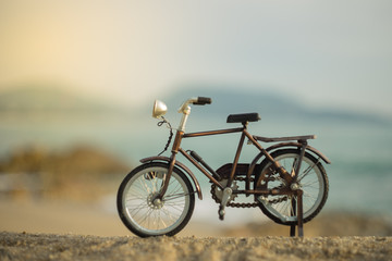 Fototapeta na wymiar bicycle transport toy on sand sea beach in the evening sunset sky , with yellow light beam