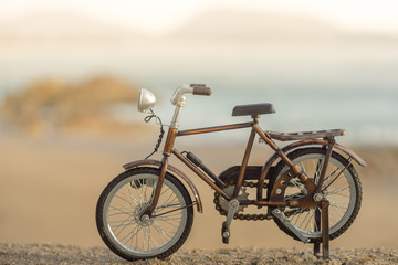 Fototapeta premium bicycle transport toy on sand sea beach in the evening sunset sky