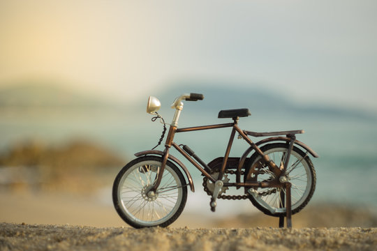 bicycle transport toy on sand sea beach in the evening sunset sky , with yellow light beam