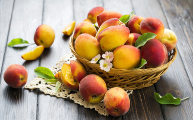 Ripe peaches in basket on wooden background